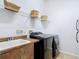 Functional laundry room with modern washer/dryer, utility sink, and storage shelves for convenience at 12637 Tyler Run Ave, Odessa, FL 33556