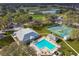 Aerial view of a community clubhouse, swimming pool, tennis courts, and surrounding greenery at 12801 Castle Oaks Dr, Hudson, FL 34669