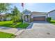 This inviting home features a two-car garage, manicured lawn, mature palm trees and classic stucco siding at 13113 Green Violet Dr, Riverview, FL 33579
