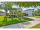 Charming single-story home with well-manicured lawn, tropical landscaping, and a paved driveway at 13113 Green Violet Dr, Riverview, FL 33579
