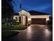 Charming one-story home featuring a tile roof, paver driveway, and well-maintained landscaping at twilight at 13113 Green Violet Dr, Riverview, FL 33579