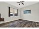 Well-lit bedroom with two windows, stylish artwork, ceiling fan, and wood-look tile flooring at 17838 Morninghigh Dr, Lutz, FL 33549