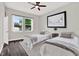 Bedroom featuring two beds, hardwood floors, ceiling fan, bright lighting, and a window at 17838 Morninghigh Dr, Lutz, FL 33549