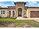 Charming home featuring a stone front facade, arched entryway, and a well-manicured front lawn at 17838 Morninghigh Dr, Lutz, FL 33549