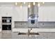 Close-up of kitchen with stainless steel appliances, white cabinets, and decorative backsplash at 17838 Morninghigh Dr, Lutz, FL 33549