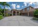 Aesthetic home featuring a three-car garage, arched entry, and a well-manicured lawn at 18434 Eastwyck Dr, Tampa, FL 33647