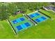 Overhead shot of four bright blue and green pickleball courts, fenced in, surrounded by green lawns and trees at 18809 Duquesne Dr, Tampa, FL 33647