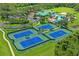 Aerial view of tennis courts, green clubhouse with a pool and palm trees in a well landscaped community at 18809 Duquesne Dr, Tampa, FL 33647
