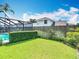 Fenced backyard with green grass and partial view of pool and screened-in enclosure at 1906 White Cedar Way, Brandon, FL 33511
