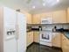 Well-lit kitchen with wooden cabinets, white appliances, and modern fixtures at 1906 White Cedar Way, Brandon, FL 33511