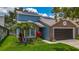 Two-story blue house with a brick facade, solar panels, beautiful landscaping, and a two-car garage at 2254 Springrain Dr, Clearwater, FL 33763