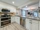 Modern white kitchen featuring stainless steel appliances, granite countertops, and wood-look floors at 2254 Springrain Dr, Clearwater, FL 33763