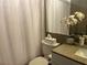 Cozy bathroom featuring patterned shower curtain, granite countertop, and stylish floral arrangement at 2500 Winding Creek Blvd # B105, Clearwater, FL 33761