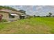 View of the backyard, featuring a large green lawn area behind a yellow house with awnings at 2609 Lancaster Dr, Sun City Center, FL 33573