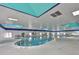 Bright indoor swimming pool with blue and white decor, ceiling skylights, and ample seating area at 2609 Lancaster Dr, Sun City Center, FL 33573