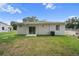A rear view of the home, including the backyard with a concrete patio and green grass at 2810 N 75Th St, Tampa, FL 33619