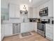 Bright kitchen featuring stainless steel appliances, white cabinets, and light wood-style flooring at 2822 W Bay Ave, Tampa, FL 33611