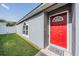 Close-up of a bright red front door with sidelight and a neat lawn at 30217 Double Dr, Wesley Chapel, FL 33545