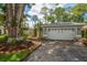 Home exterior featuring an attached two-car garage, stone accents, and meticulous landscaping at 3273 Tanglewood Trl, Palm Harbor, FL 34685