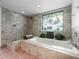 Bright bathroom featuring a soaking tub, tiled shower, and stained glass window offering natural light at 3305 Westmoreland Dr, Tampa, FL 33618