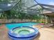 Pool with hot tub, surrounded by a screened enclosure and lush backyard landscaping at 3305 Westmoreland Dr, Tampa, FL 33618