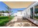 Backyard patio featuring chairs, a shade cover, and a view of the green lawn next to a white home at 434 77Th Ave, St Pete Beach, FL 33706