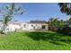 Backyard with a well-maintained lawn, a patio area, and a charming white house with a black roof at 434 77Th Ave, St Pete Beach, FL 33706