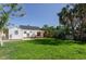 Backyard view with green lawn, patio area, shade sail, and a charming white house with black roof at 434 77Th Ave, St Pete Beach, FL 33706