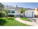 Charming home with palm trees, a green lawn, and a driveway that leads to an attached garage at 434 77Th Ave, St Pete Beach, FL 33706