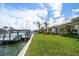 Waterfront property with dock, lush lawn, and stunning canal views with palm trees and blue skies at 4545 Clearwater Harbor N Dr, Largo, FL 33770