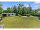 Large green backyard with an open shed, cinder block building, lawn, and trees in the background at 459 Bell Ave, Brooksville, FL 34601
