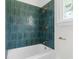 This renovated bath has teal glass subway tile, gold fixtures and vintage shower at 459 Bell Ave, Brooksville, FL 34601