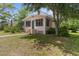 Exterior shot showcasing a cute single-Gathering home with a screened porch, lawn and mature trees at 459 Bell Ave, Brooksville, FL 34601