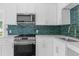 Close-up of the kitchen area showcasing stainless steel appliances, white cabinetry, and a modern tile backsplash at 459 Bell Ave, Brooksville, FL 34601