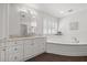 Bright primary bathroom features an oval tub, dark tile flooring, vanity, and shutters at 460 Althea Rd, Belleair, FL 33756