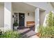 A welcoming front porch offers seating next to a black door with updated hardware at 460 Althea Rd, Belleair, FL 33756