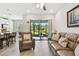 Bright living room with a leather sofa, accent chair, ceiling fan, and sliding glass doors to the patio at 4653 Ancona Way, Wesley Chapel, FL 33543