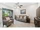 Cozy living room with a leather sofa, arm chair, ceiling fan, and sliding glass door to the patio at 4653 Ancona Way, Wesley Chapel, FL 33543