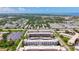 Wide aerial view of a multi-building condo complex with parking, mature trees and distant ocean view at 5603 80Th N St # 103, St Petersburg, FL 33709