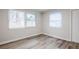 Cozy bedroom with two windows offering natural light, complemented by neutral paint and wood-look floors at 5847 Harrison St, New Port Richey, FL 34653