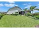 Beautiful backyard with lush green grass, tropical palms, black metal fencing, and screened in porch at 5971 Hidden Branch Dr, Apollo Beach, FL 33572
