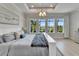 Spacious main bedroom with large windows showcasing backyard view and tray ceiling with modern chandelier at 5971 Hidden Branch Dr, Apollo Beach, FL 33572