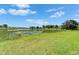Scenic view of a tranquil pond surrounded by lush green grass and distant trees at 5971 Hidden Branch Dr, Apollo Beach, FL 33572