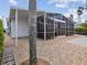 Exterior view of an outdoor screened room featuring a dining area and a brick paver patio at 6531 Seaview Blvd, Hudson, FL 34667