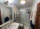 Well-lit bathroom with glass shower, decorative shelf, vanity and marble-style tiling at 6531 Seaview Blvd, Hudson, FL 34667