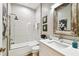 Bathroom with tiled shower, white vanity, quartz counters, and rustic framed mirror at 6606 Pullen Ct, Tampa, FL 33625