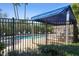 Community pool area with lounge chairs, a blue awning, black fencing, and a tranquil setting at 6606 Pullen Ct, Tampa, FL 33625