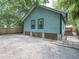Exterior of light blue home with windows, crawl space, and fenced in backyard with green foliage at 708 E Patterson St, Tampa, FL 33604