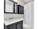 Bathroom with dark vanity, shower with white curtain and white tiled walls at 708 E Patterson St, Tampa, FL 33604