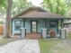 Inviting bungalow with blue siding, wood porch, decorative pillars, and tidy landscaping at 708 E Patterson St, Tampa, FL 33604